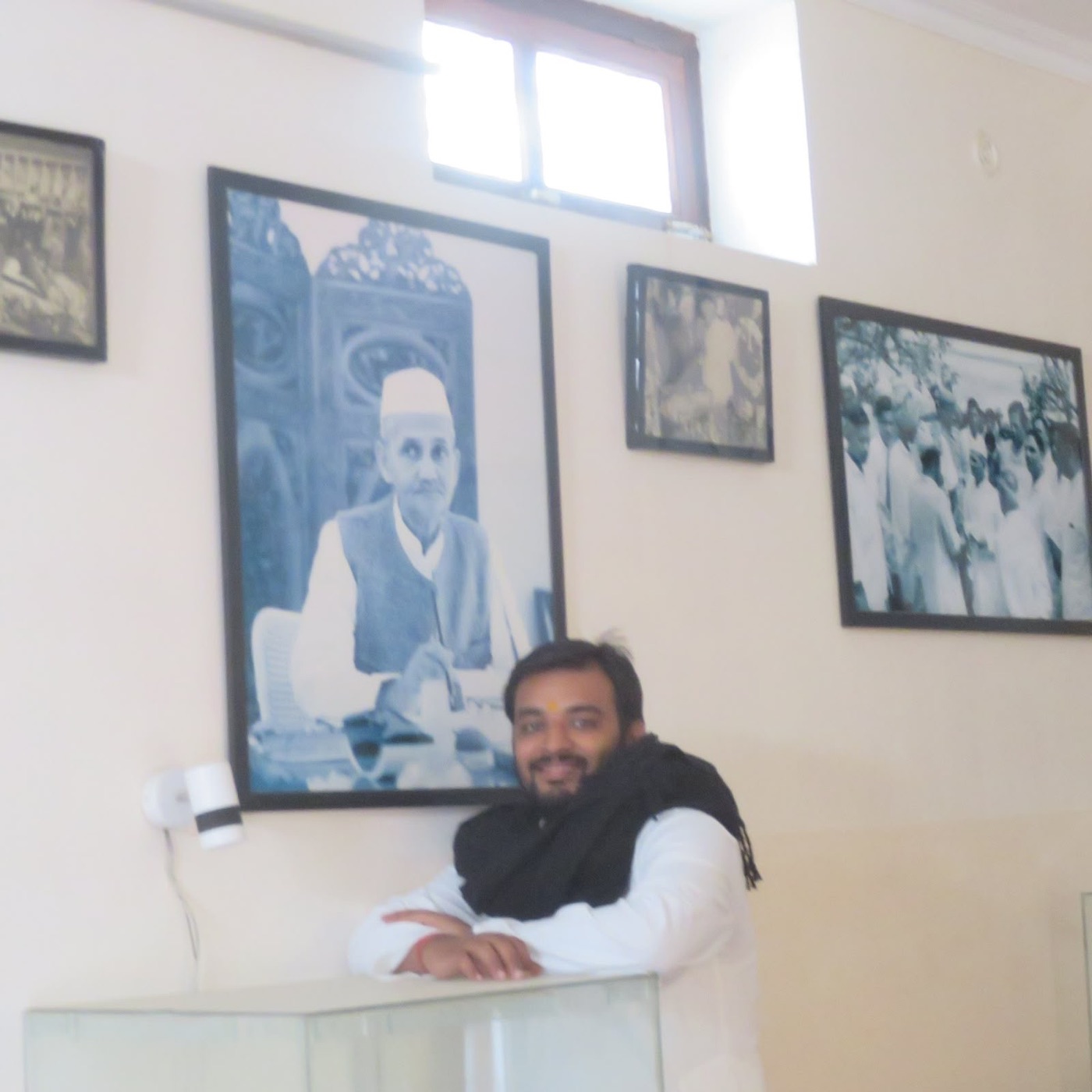 Himanshu Tiwari beside a wall of archival photographs of freedom fighters